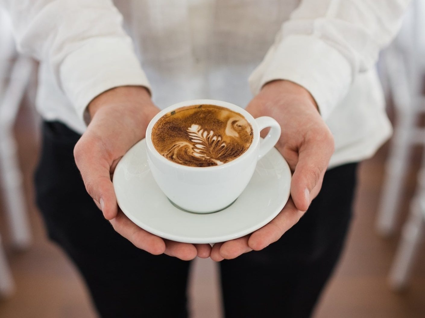 Flat white coffee in white cup held by two hands